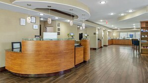 A hotel reception area with a curved reception desk, multiple computer monitors, and a seating area with a counter. - Comfort Suites At Kennesaw State University (Kennesaw)