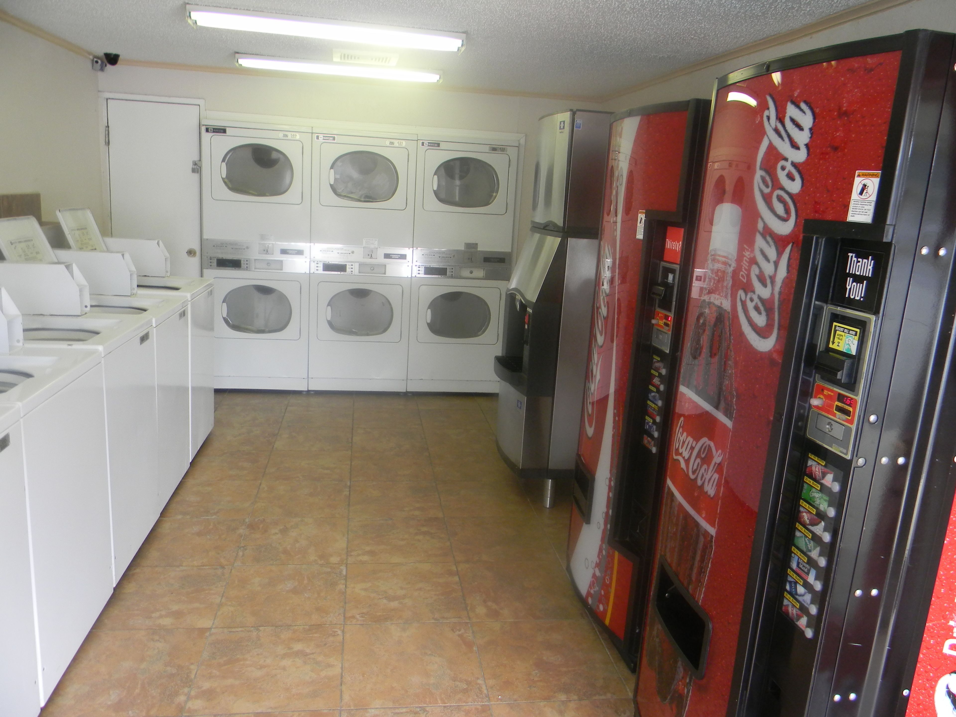 A laundromat with multiple washing machines and a Coca-Cola vending machine.