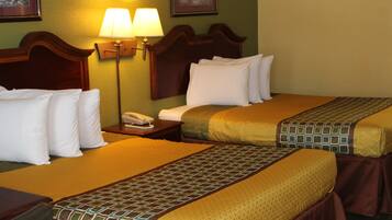 A hotel room with two beds, each with a patterned bedspread, a nightstand with a lamp, and a framed picture on the wall.