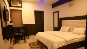 A neatly arranged bedroom with a bed, a desk, and a chair. - South Indian Hotel (New Delhi)