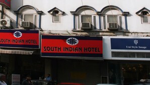 A building with multiple windows and a sign for the South Indian Hotel. - South Indian Hotel (New Delhi)