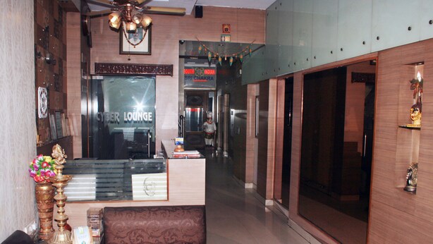 A lobby with a reception desk, a sofa, and a statue. - South Indian Hotel (New Delhi)