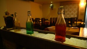 A bar area with bottles of beverages on ice. - South Indian Hotel (New Delhi)