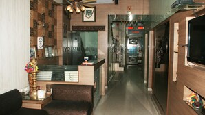A hotel lobby with a reception desk, seating area, and a staircase leading to other floors. - South Indian Hotel (New Delhi)