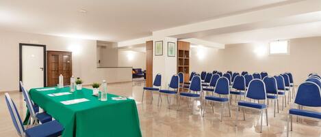 A conference room with a green table, blue chairs, and a tiled floor.