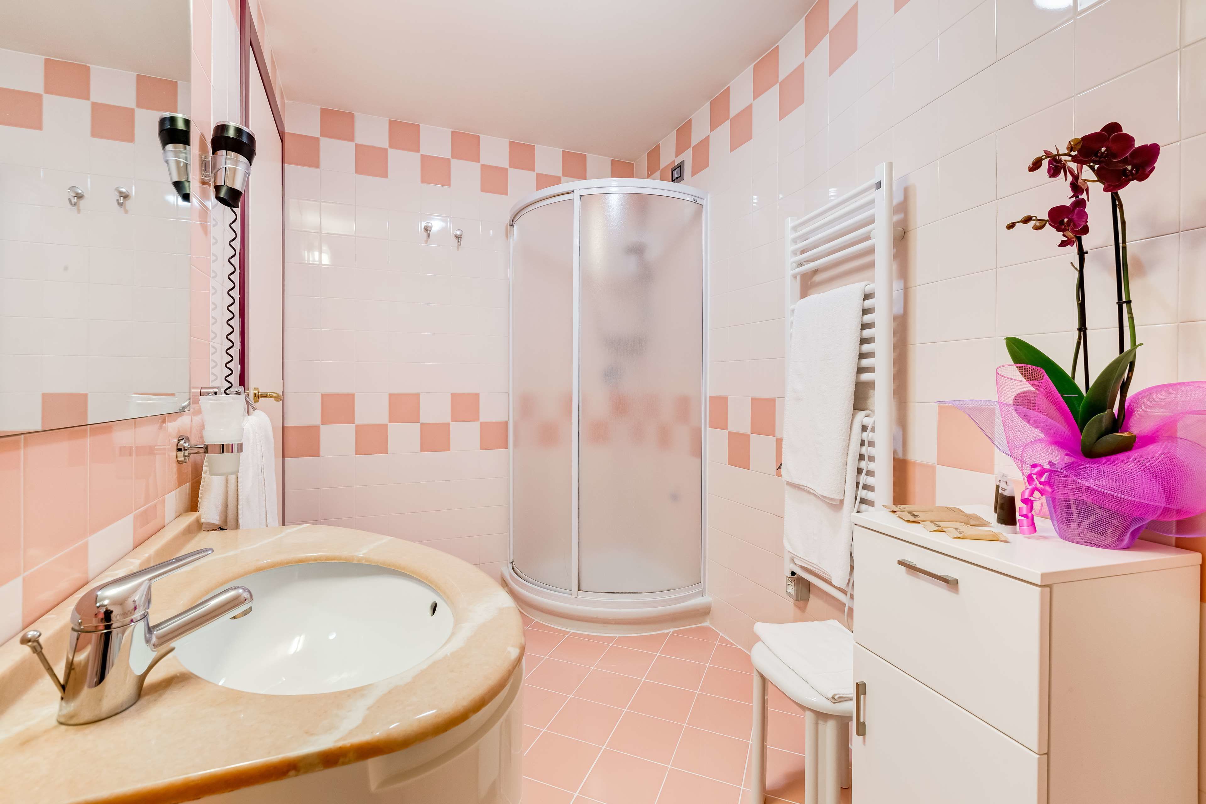 A bathroom with a sink, mirror, shower, and a cabinet with a towel.