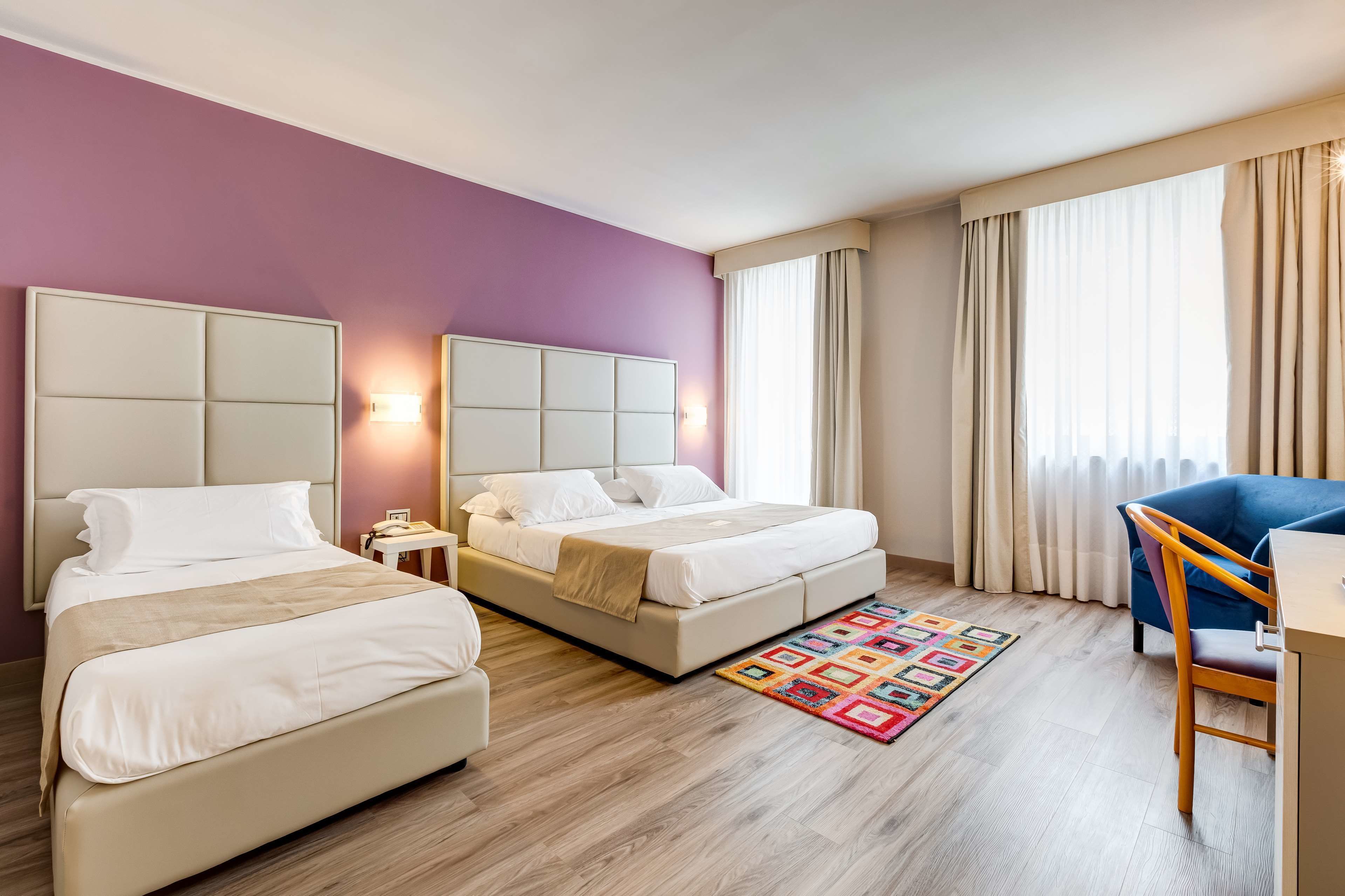 Habitación de hotel con dos camas, un escritorio y una silla.