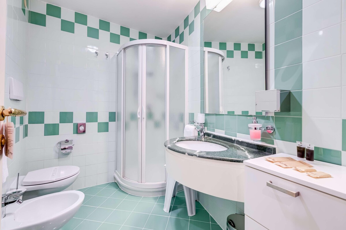 Un baño con ducha, inodoro, lavabo y espejo.