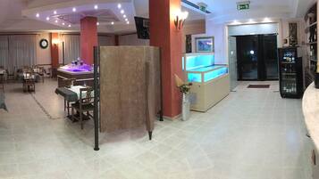 Un vestíbulo de hotel con mostrador de recepción, zona de estar y un gran acuario.