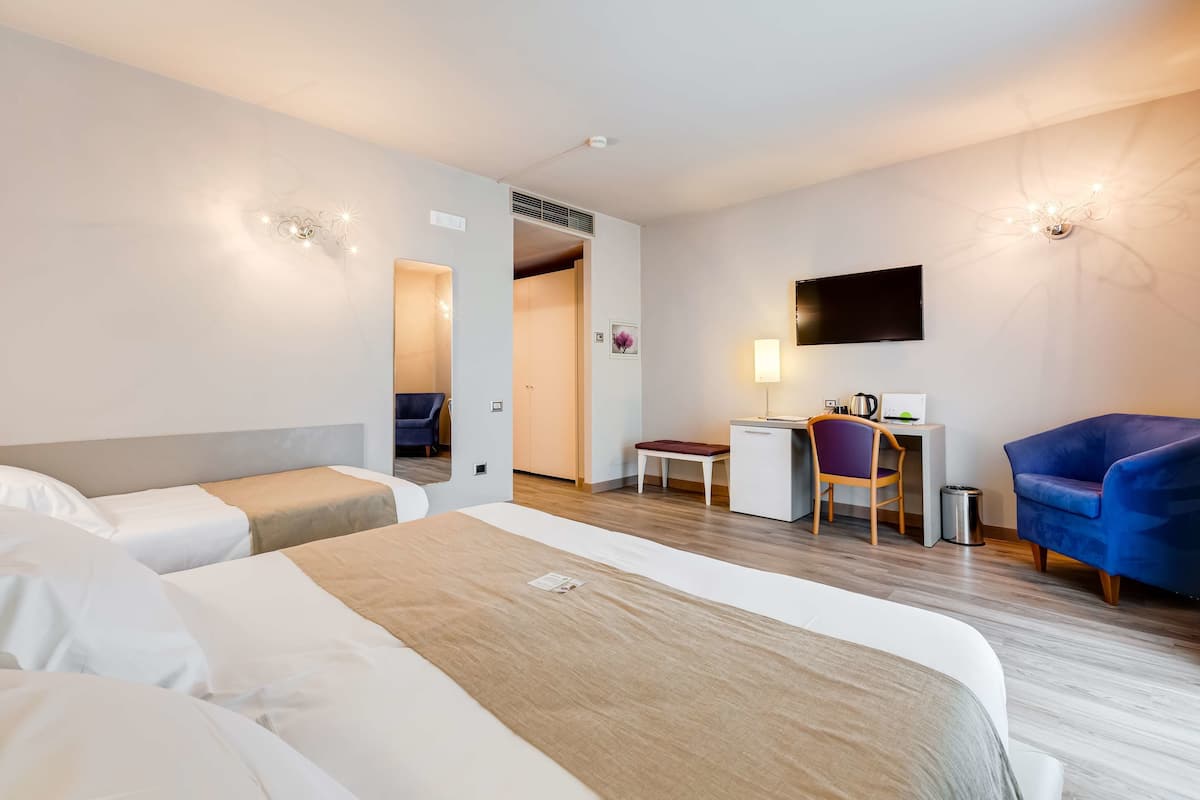 Une chambre d’hôtel avec un lit, un bureau, une chaise et un téléviseur.
