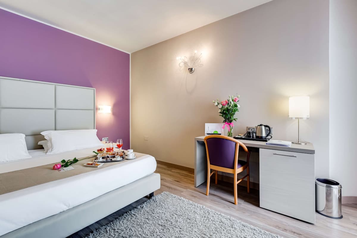 Une chambre d’hôtel moderne équipée d’un lit, d’un bureau, d’une chaise et d’une petite kitchenette.