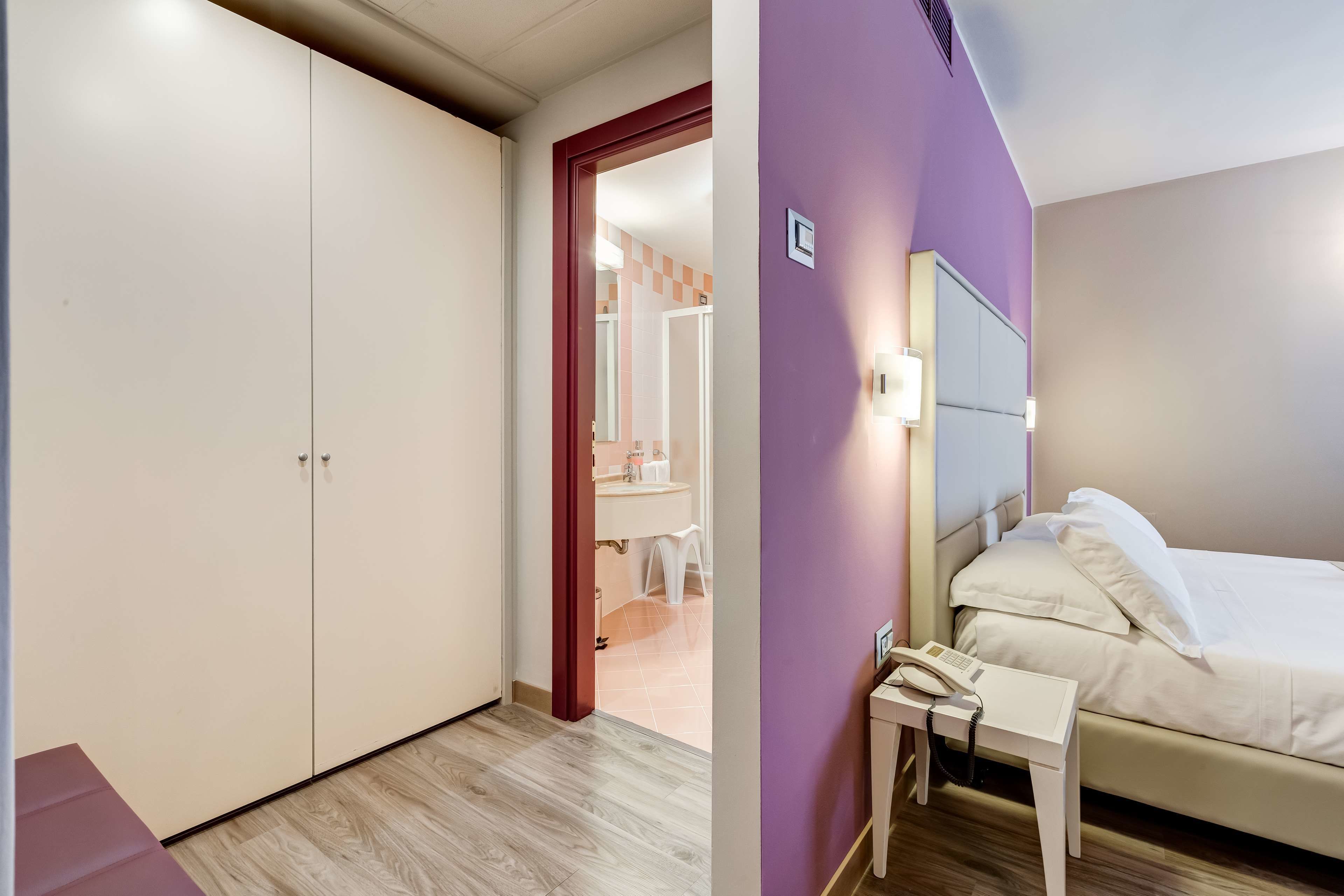 Una habitación de hotel con cama, mesita de noche y armario.