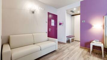 A modern hotel lobby with a beige sofa, a red door, and a purple accent wall.