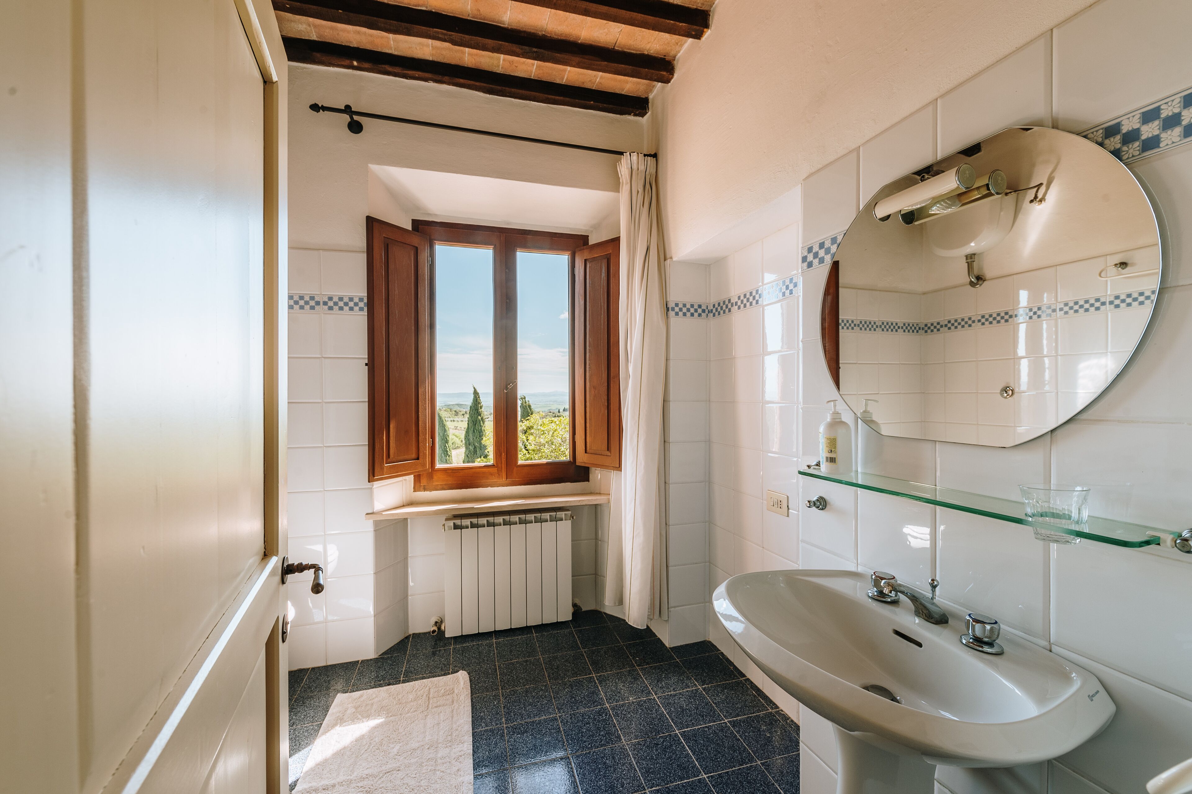 A bathroom with a window, a sink, and a mirror.