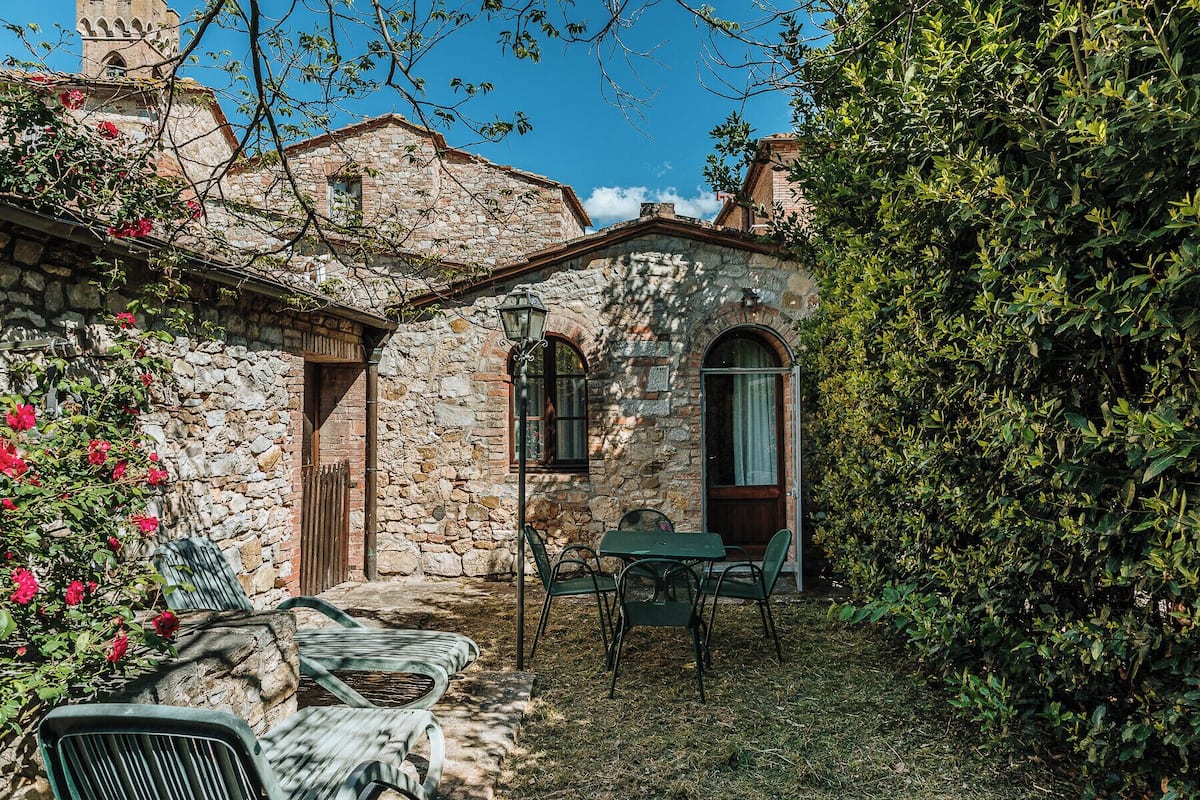 Ein Steinhaus mit einer kleinen Terrasse, einem Tisch und Stühlen.