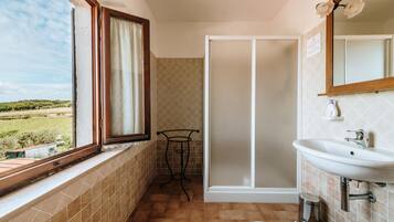 Une salle de bain avec une fenêtre, un lavabo et une douche.