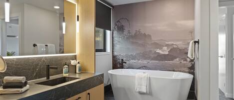 Un baño moderno con una bañera independiente, un espejo grande y un lavabo empotrado.
