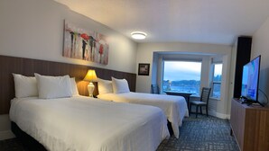 Une chambre d’hôtel avec deux lits, un bureau, une chaise, une télévision et un tableau au mur.