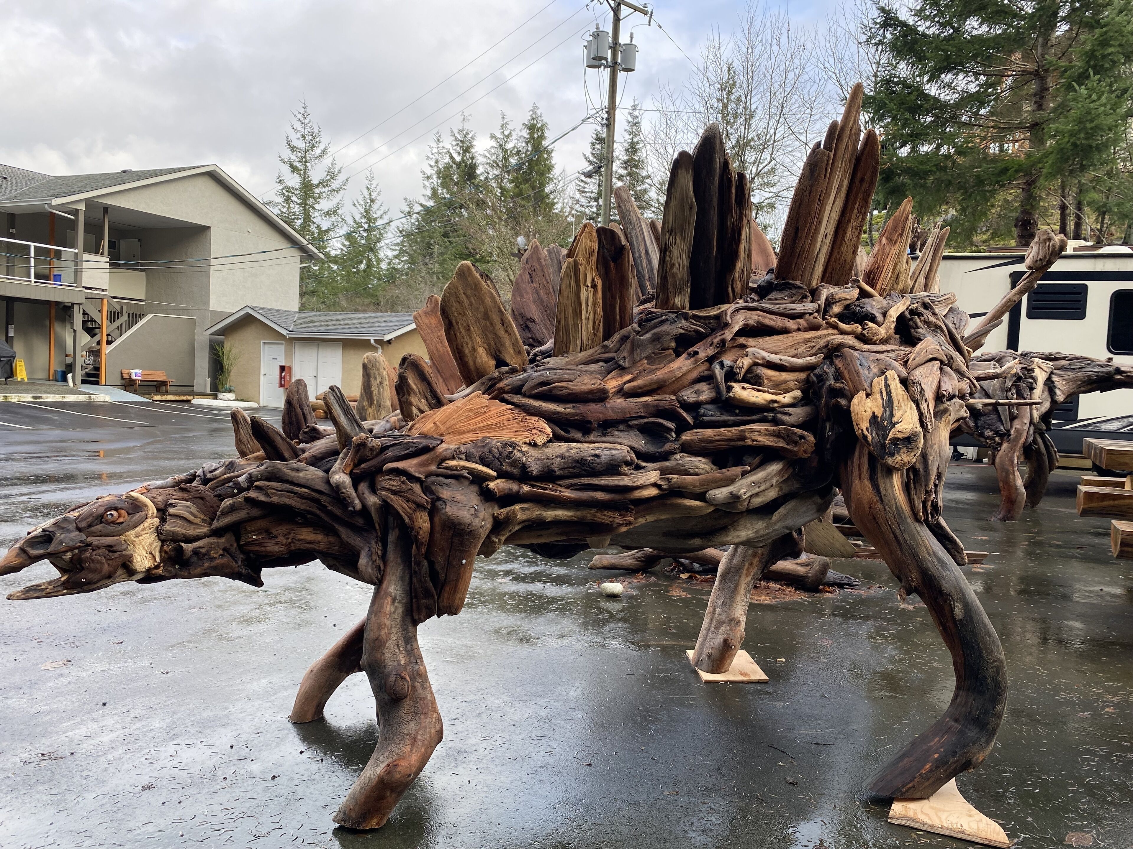 Une grande sculpture en bois représentant un dinosaure, exposée en plein air.