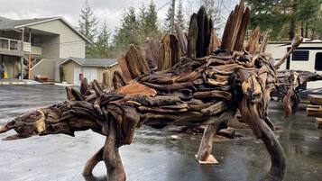 Une grande sculpture en bois représentant un dinosaure, exposée en plein air.
