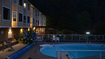 Un hotel con piscina, mobiliario exterior y un arreglo floral.
