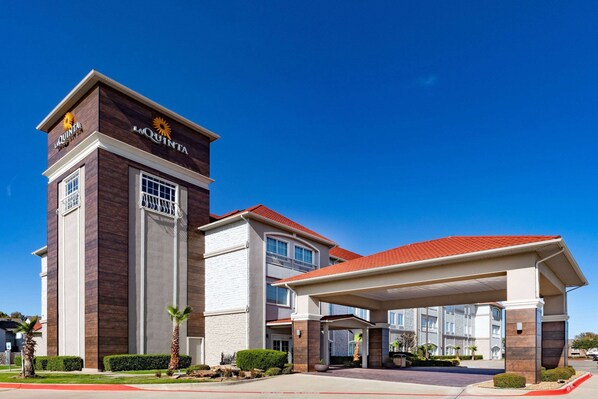 Un hotel con una torre destacada, una entrada cubierta y un exterior bien conservado.