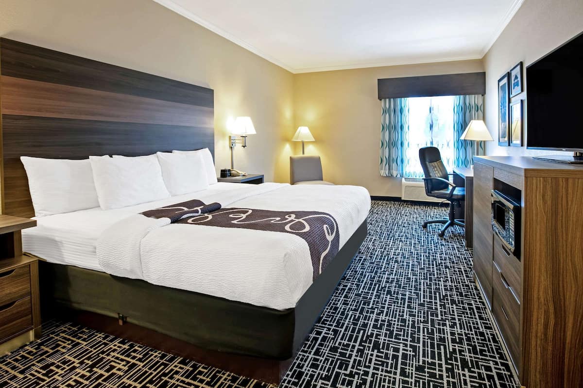 Hotelkamer met een groot bed, een bureau, een stoel, een televisie en een raam met gordijnen.