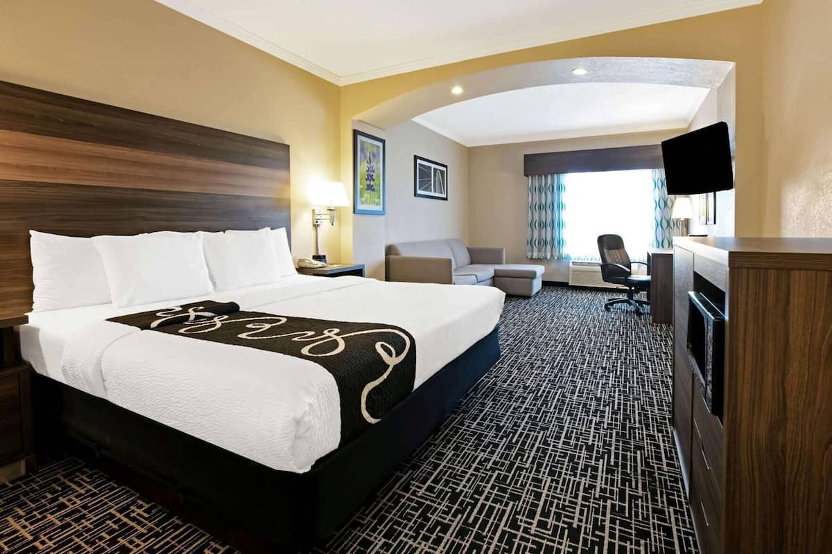 Een hotelkamer met een groot bed, een bureau, een stoel, een televisie en een raam met gordijnen.