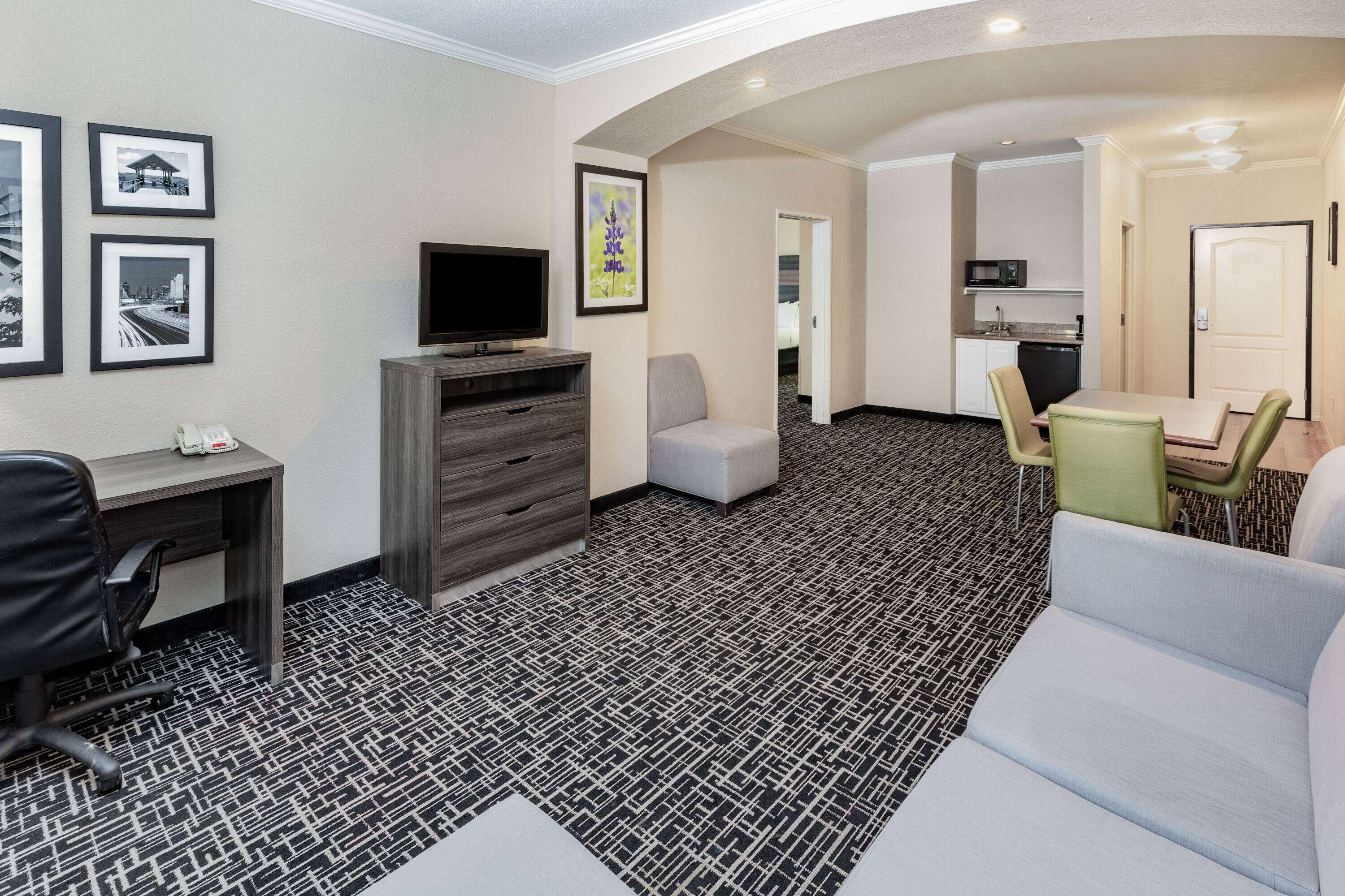 Una habitación de hotel con escritorio, televisión, sofá, comedor y cocina.