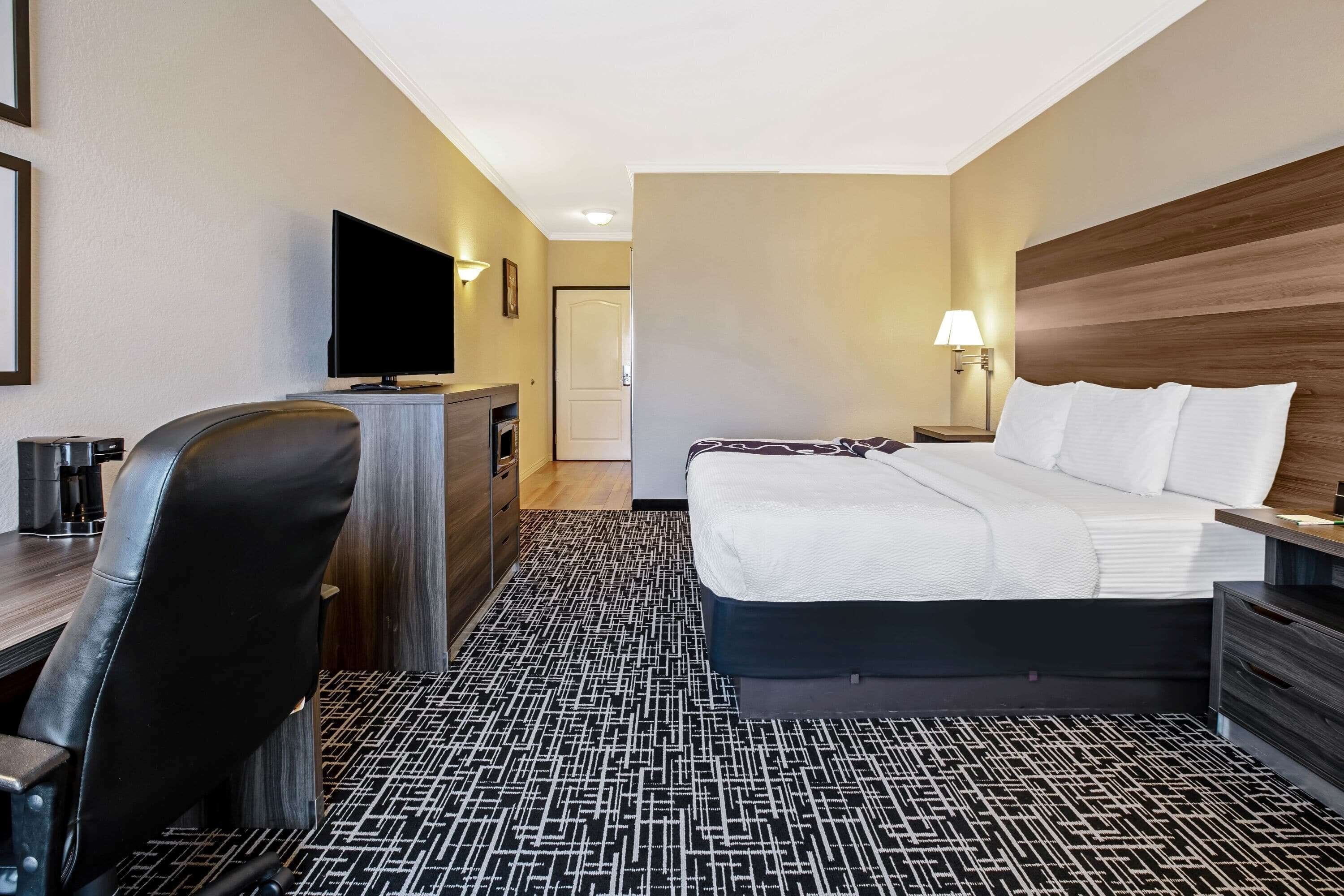 Une chambre d’hôtel comprenant un lit, un bureau avec une chaise, une télévision et une lampe.