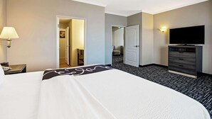 Habitación de hotel con una cama grande, televisión, escritorio con lámpara y armario.