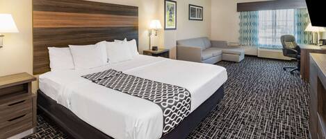 Une chambre d’hôtel avec un grand lit, un bureau, une chaise et un canapé.