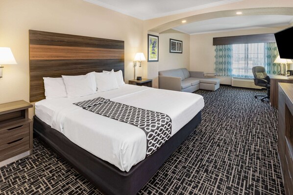 Una habitación de hotel con una cama grande, un escritorio, una silla y un sofá.