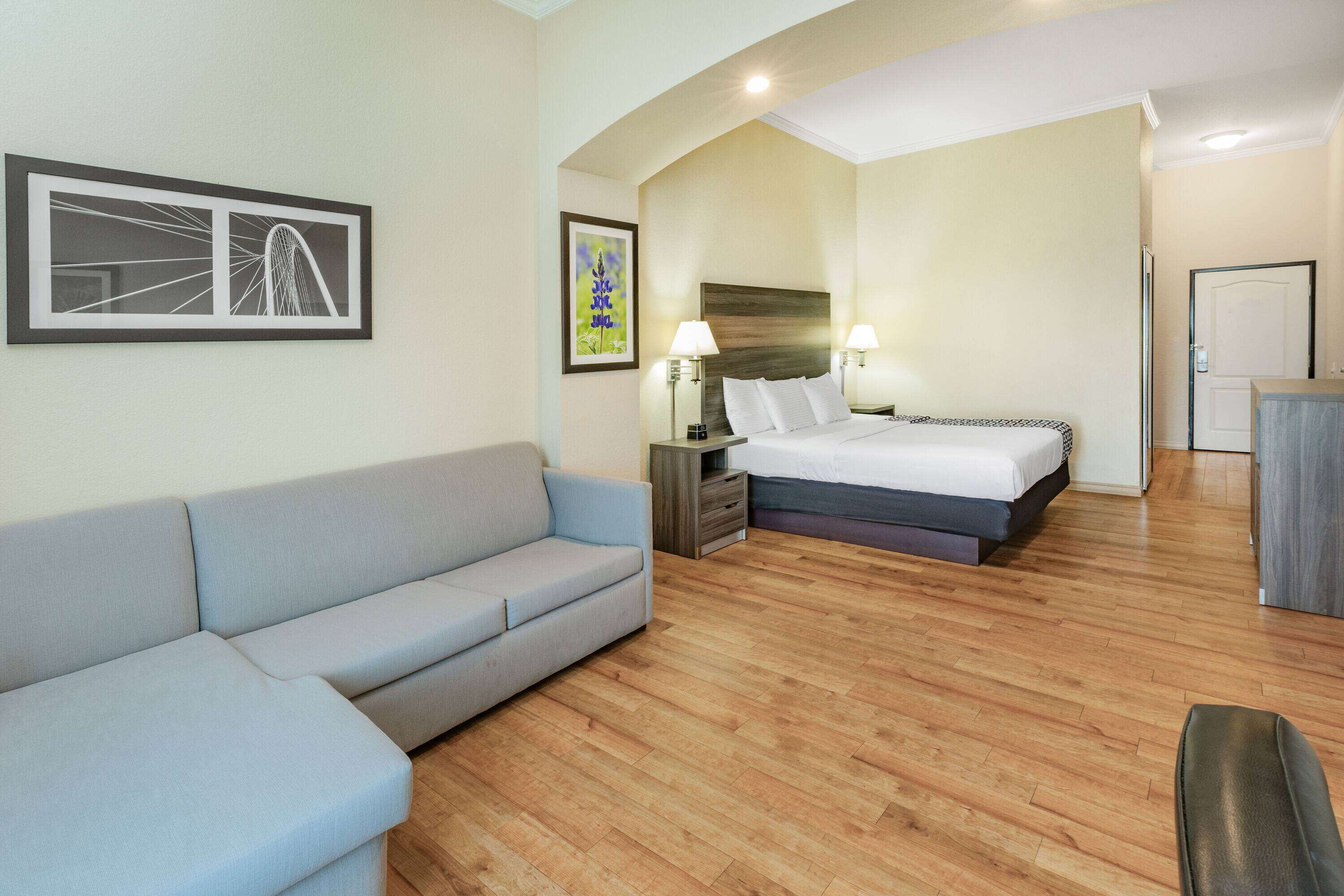 Une chambre d’hôtel avec un canapé, un lit, une table de chevet et un tableau accroché au mur.
