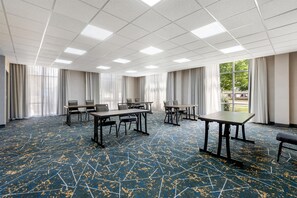 A conference room with a high ceiling, rectangular tables, and chairs, large windows with curtains, and a patterned carpet. - Hampton Inn & Suites Charlotte Airport (Charlotte)