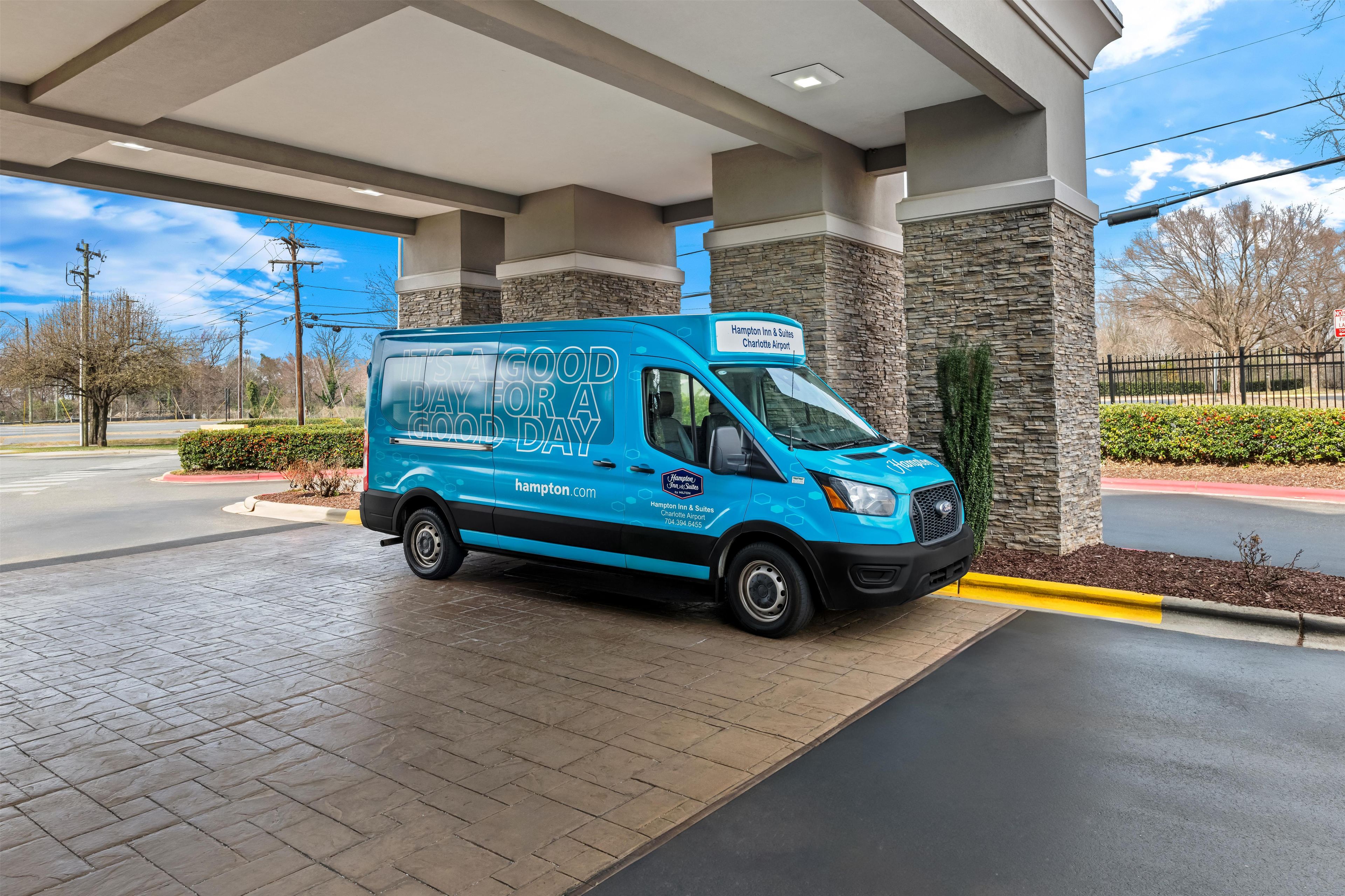 A blue Hampton Inn & Suites van parked at a gas station.