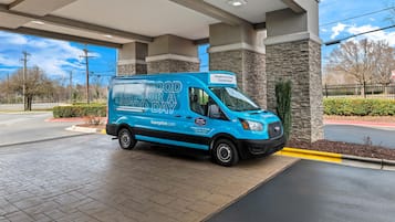 A blue Hampton Inn & Suites van parked at a gas station.
