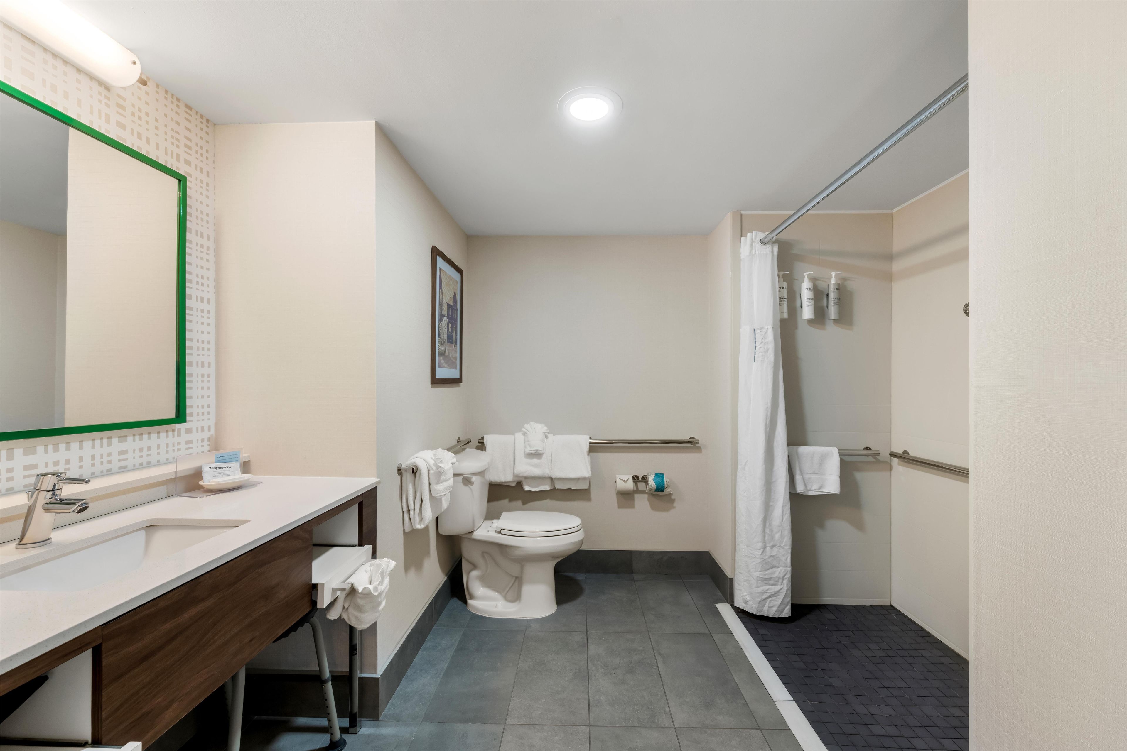 A bathroom with a sink, mirror, toilet, and shower.