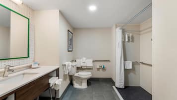 A bathroom with a sink, mirror, toilet, and shower.