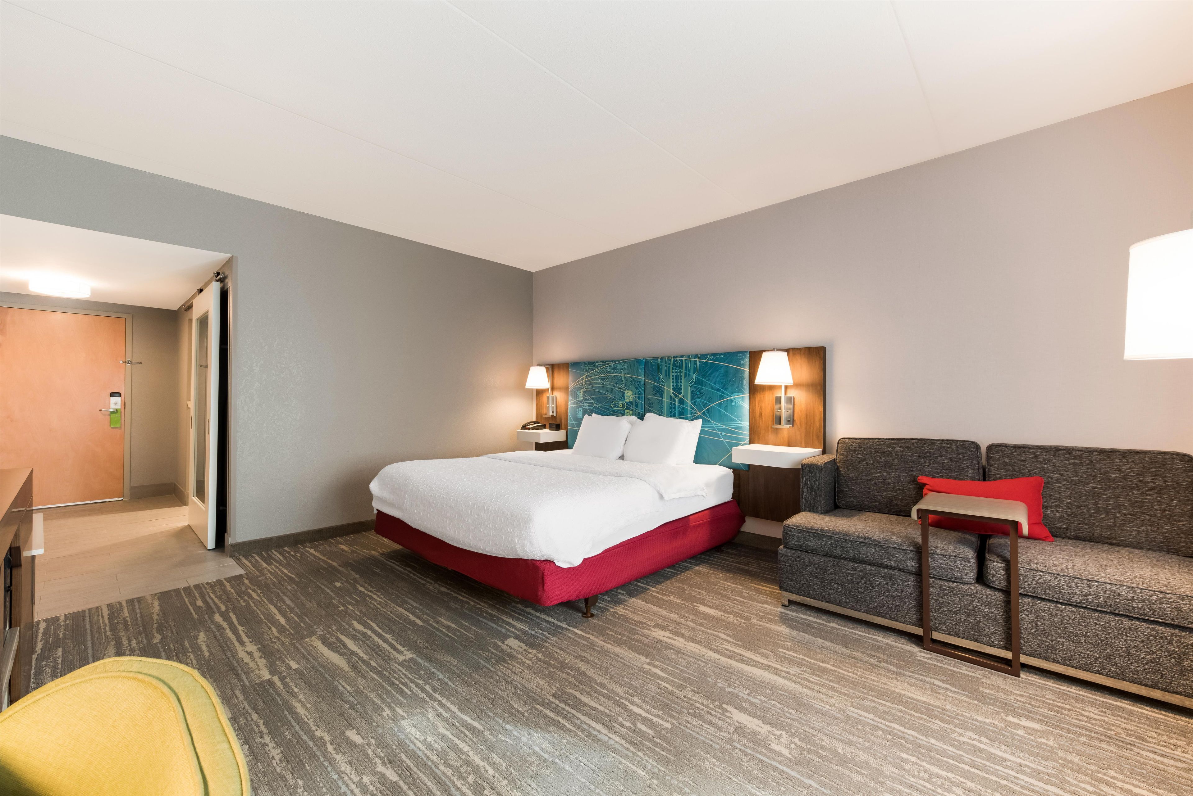 A hotel room with a bed, a sofa, a small table, and a chair.