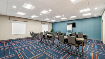 Ein Konferenzraum mit blauem Teppich, weißen Wänden und einer Decke mit eingelassener Beleuchtung.