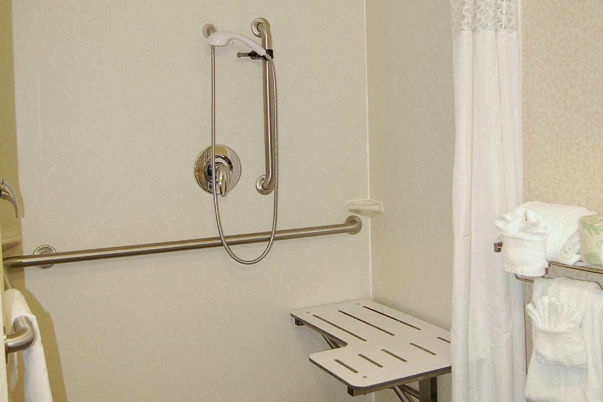 A bathroom with a shower, grab bar, and a towel rack.