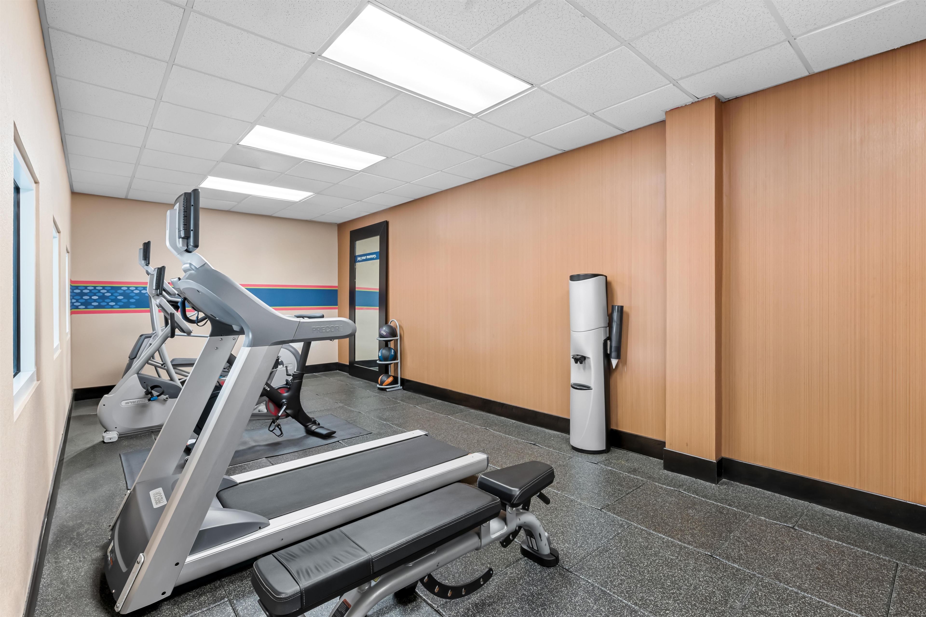 A gym with treadmills, a stationary bike, and a wall-mounted exercise machine.