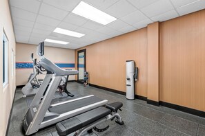 A gym with treadmills, a stationary bike, and a wall-mounted exercise machine. - Hampton Inn & Suites Charlotte Airport (Charlotte)