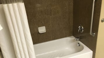 A bathroom with a bathtub, a shower, and a handrail.