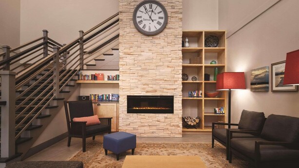 Een moderne woonkamer met een open haard, een trap en een boekenkast.