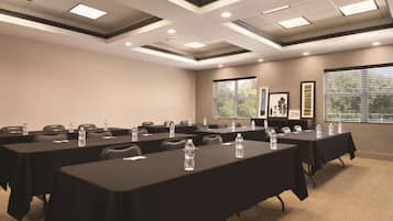 Uma sala de conferências com várias mesas, cadeiras e garrafas de água.