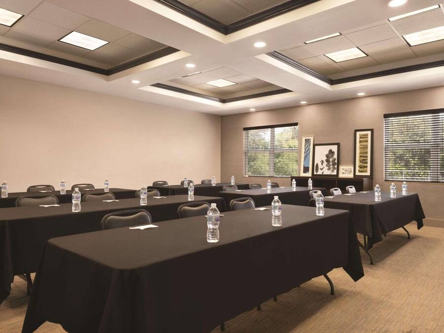 Uma sala de conferências com várias mesas, cadeiras e garrafas de água.