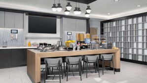 A modern kitchen with a central island, bar stools, and a built-in coffee machine.