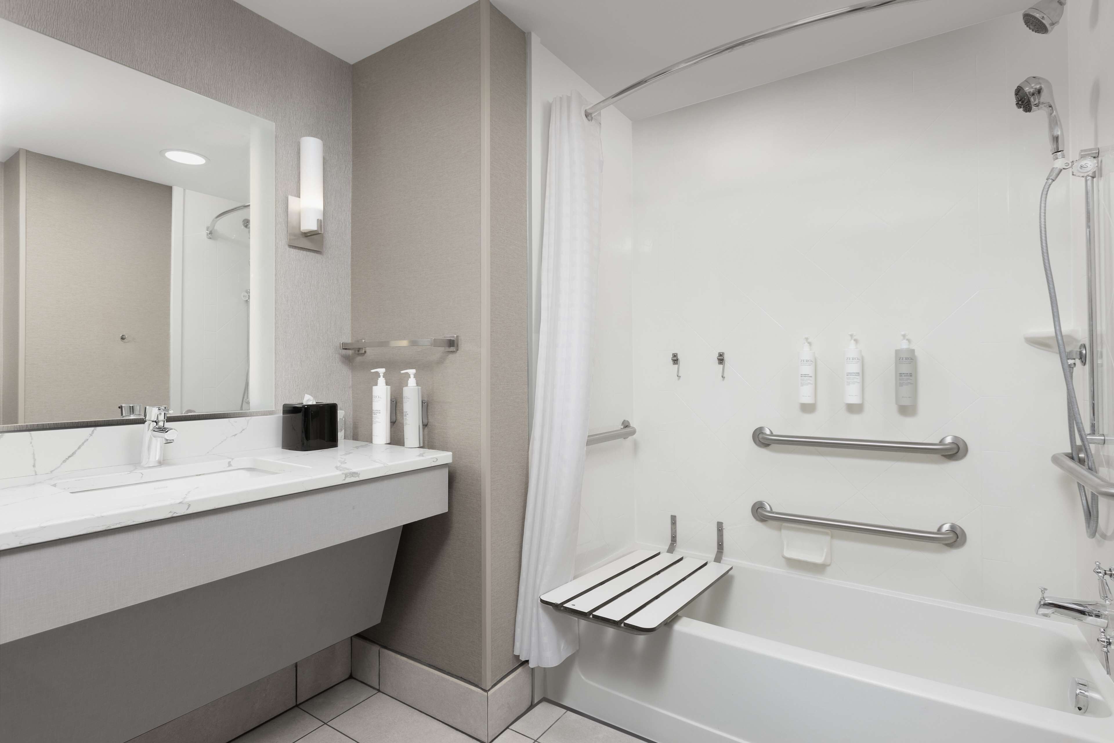 A modern bathroom with a white sink, mirror, and shower.